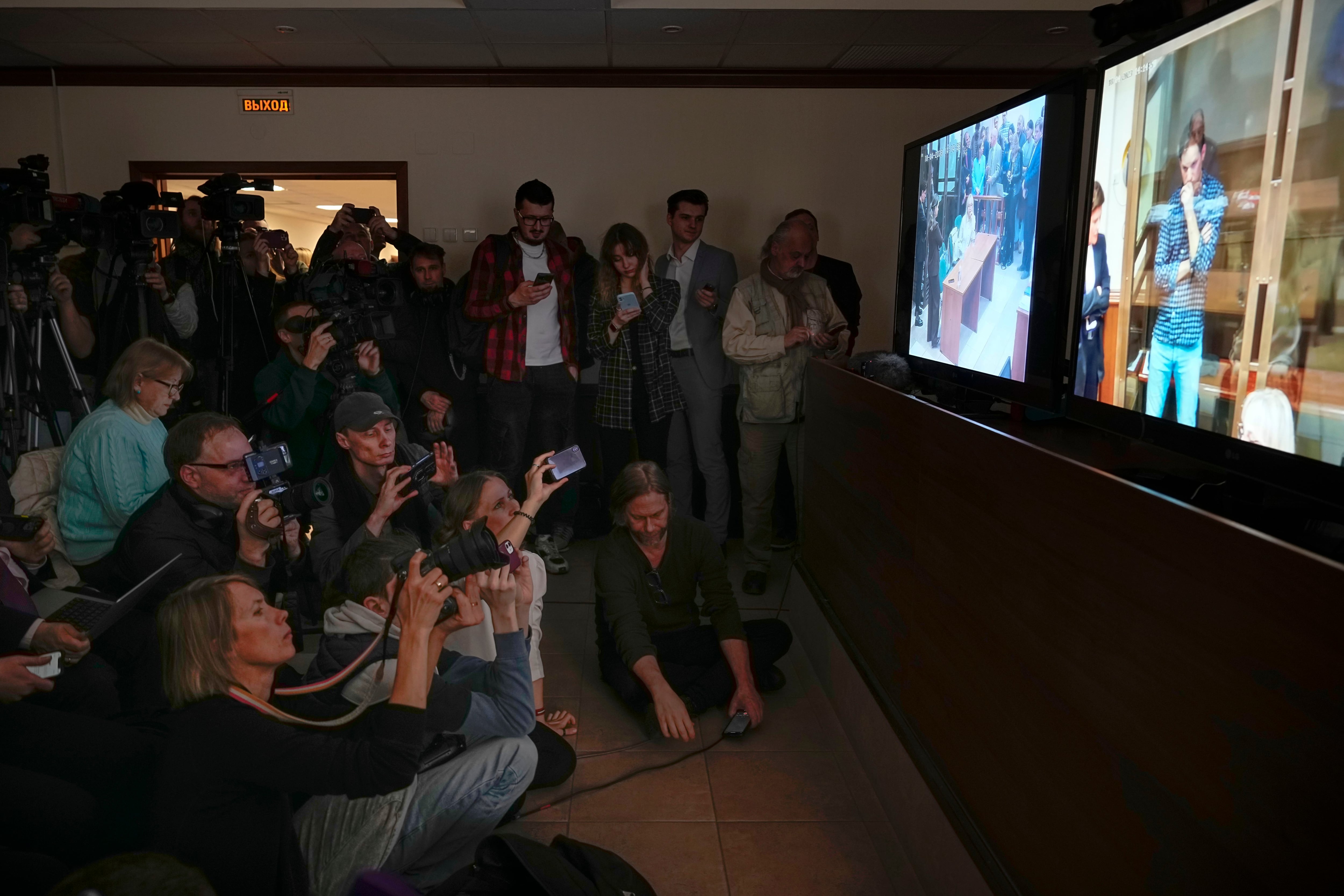Journalists watch a TV screen broadcasting a hearing on Wall Street Journal reporter Evan Gershkovich's case from a courtroom at the Moscow City Court on April 18, 2023.