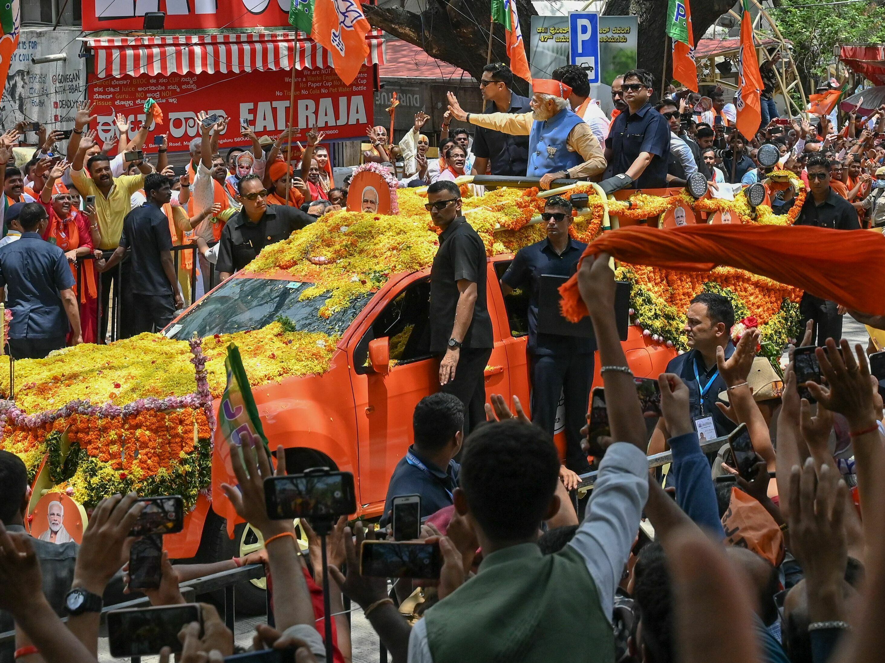 Indian Prime Minister Narendra Modi waves to supporters from atop a vehicle during a road rally held by the Bharatiya Janata Party (BJP) in Bengaluru on May 6, 2023.