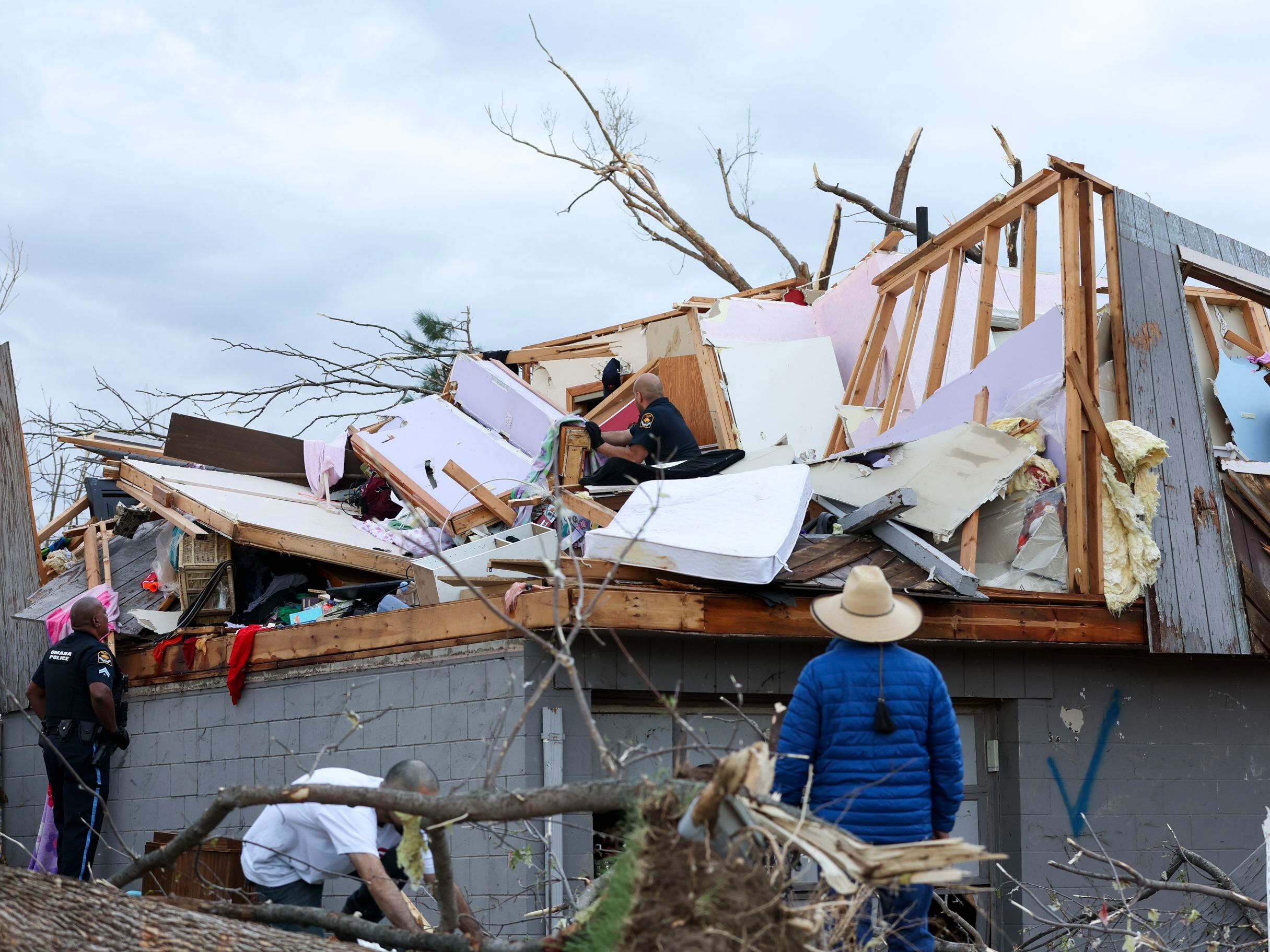Omaha police officers search a home for a family after a tornado leveled dozens of homes near Omaha, Neb., on Friday, April 26, 2024.