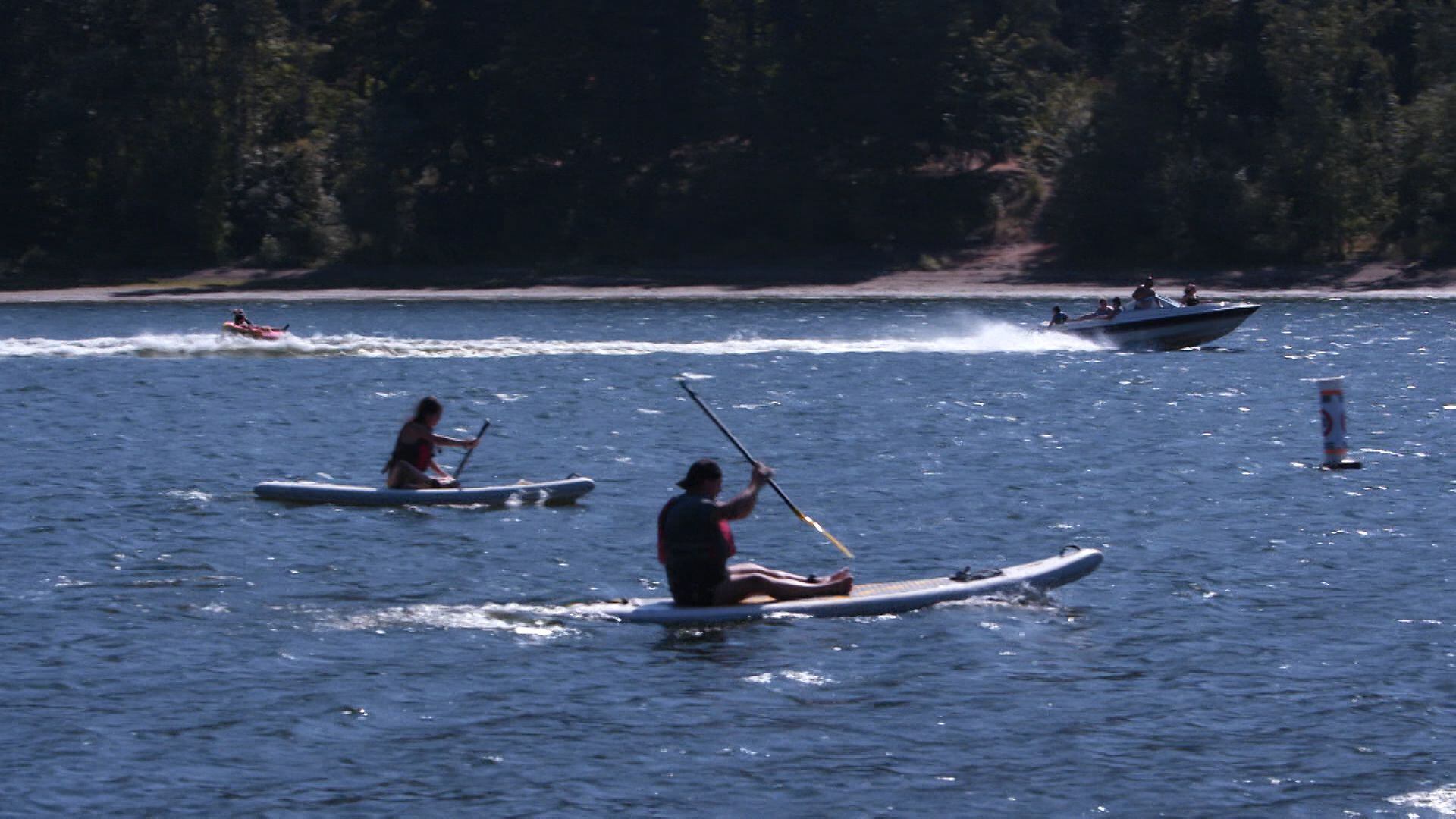 Stand-up paddleboarders pass through a no-wake zone near a group of floating homes where towed water sports like tubing are no longer allowed from May through September on this crowded stretch of the Willamette River.