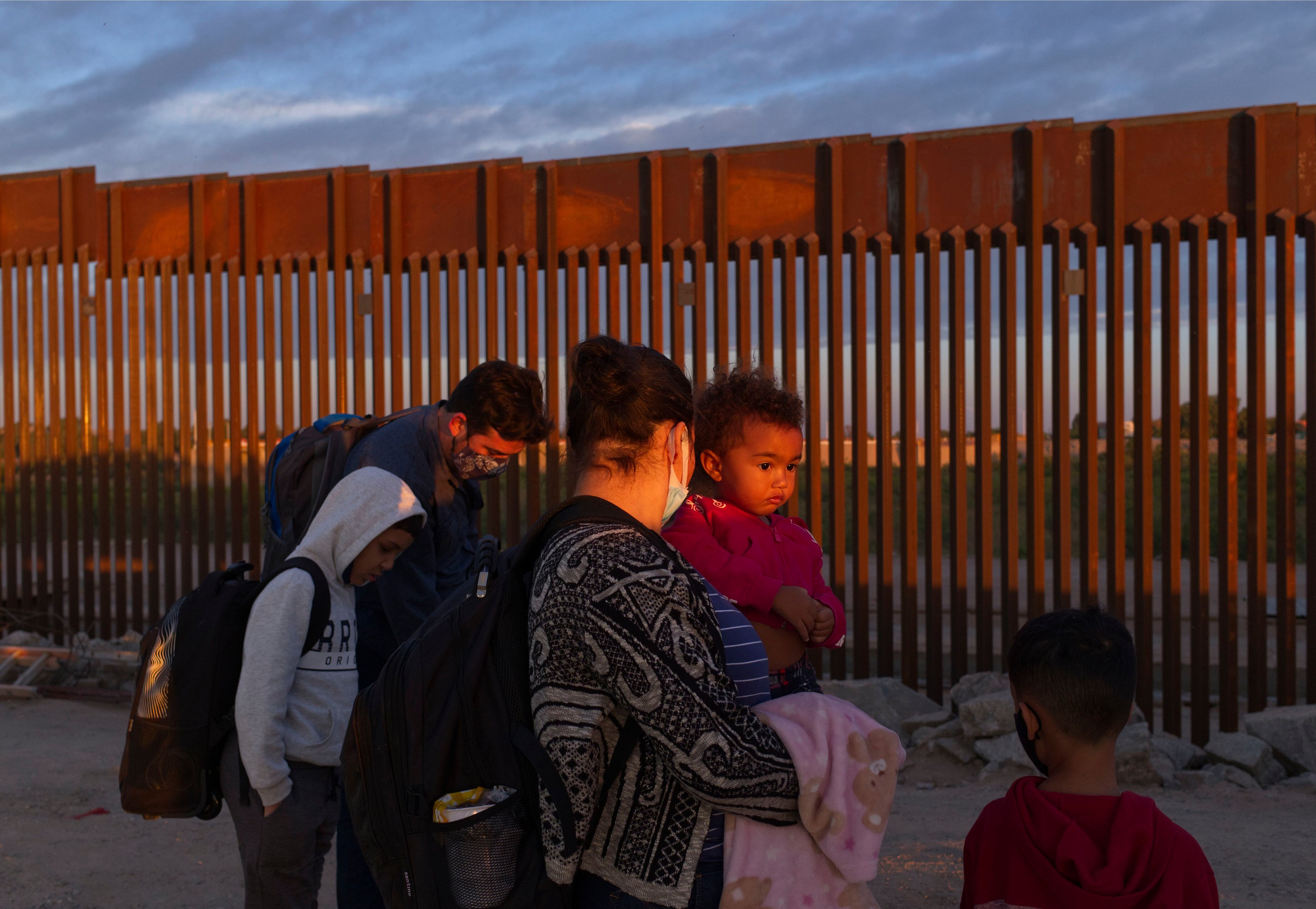 FILE - A pair of migrant families from Brazil wait to be processed by U.S. Border Patrol agents after passing through a gap in the border wall from Mexico in Yuma, Ariz., Thursday, June 10, 2021, to seek asylum.
