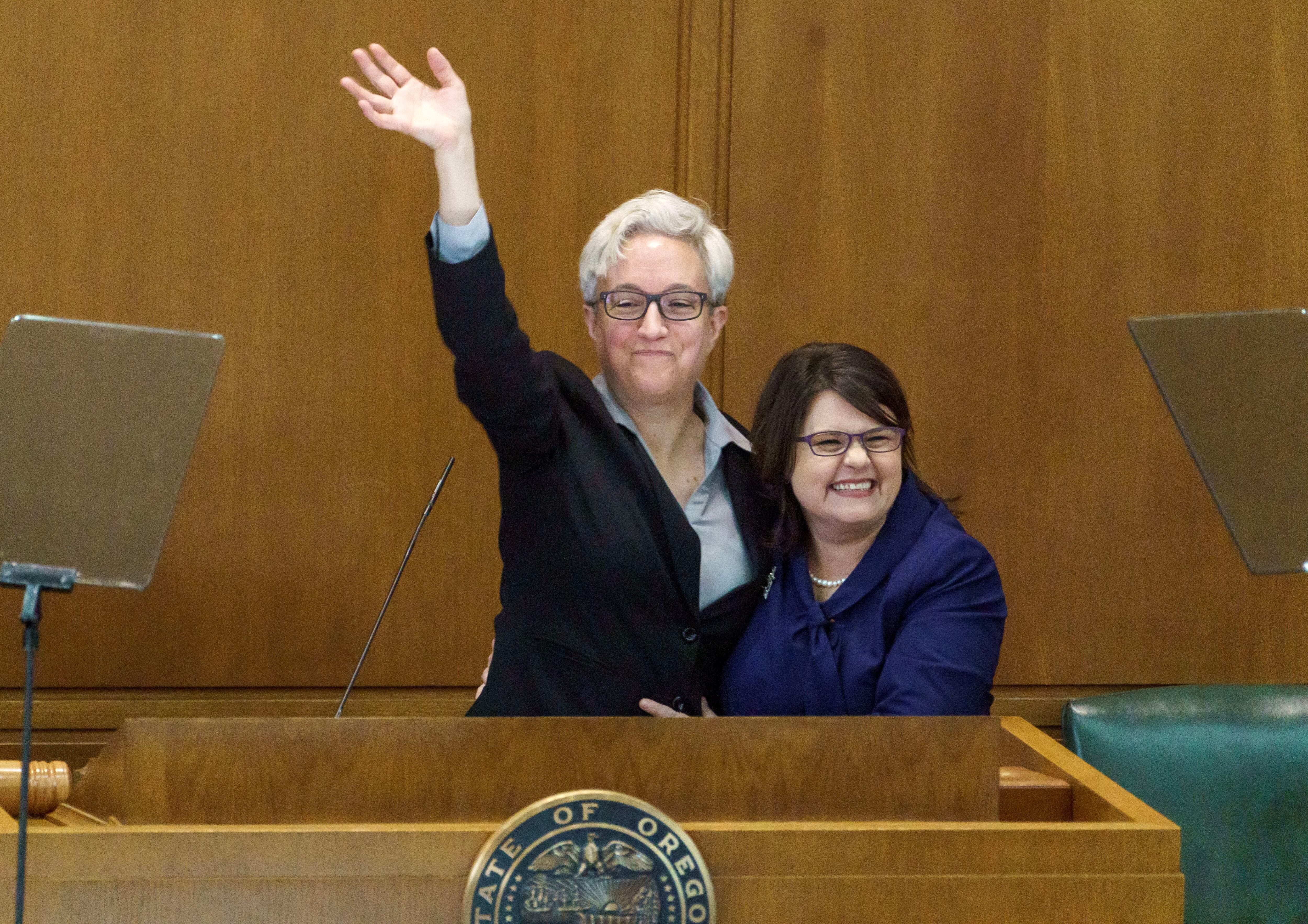 Gov. Tina Kotek waves to the crowd, along with her wife, Aimee Kotek Wilson, after being sworn into office at the Oregon Capitol in Salem, Ore., Jan. 9, 2023.