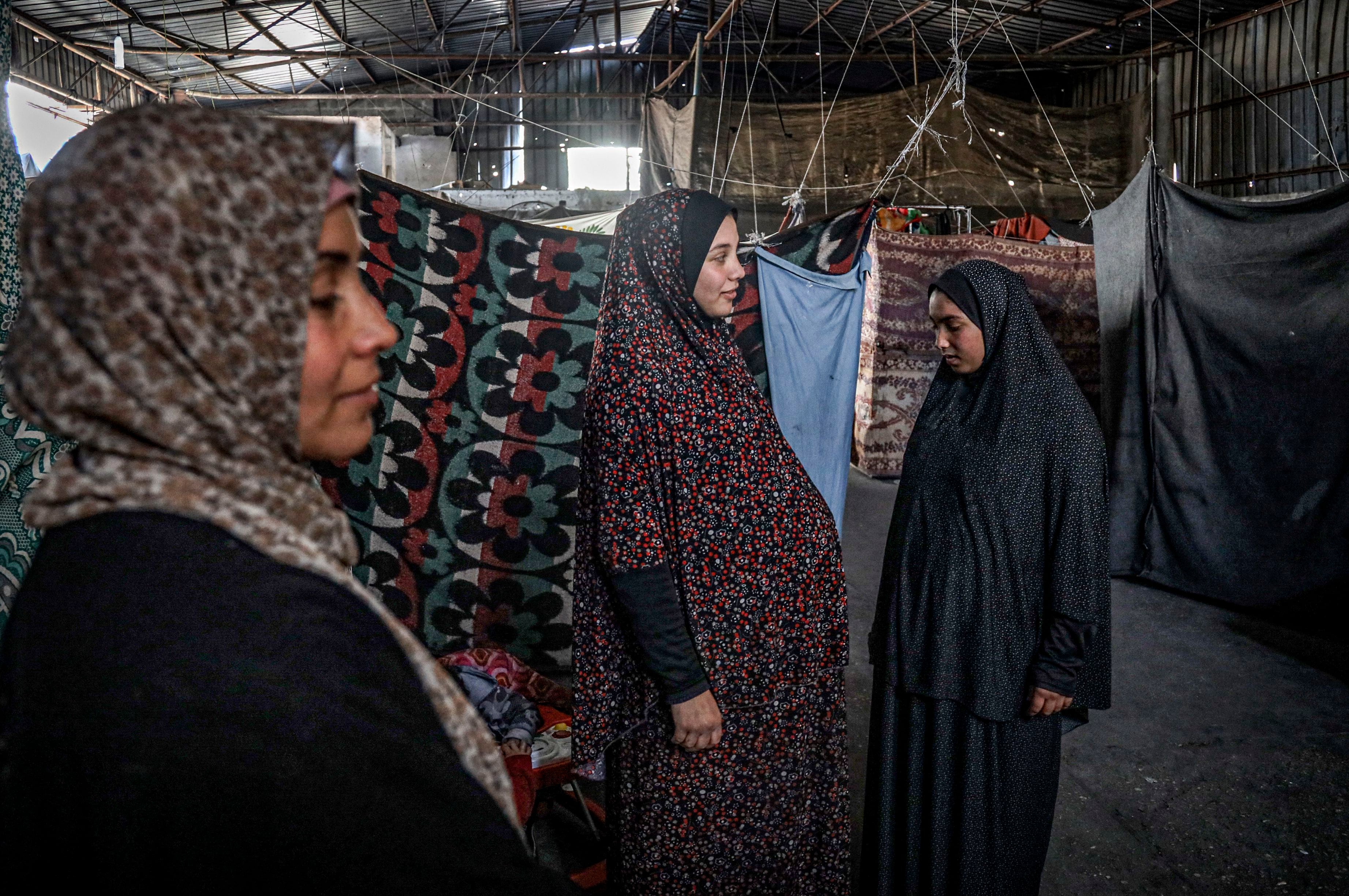 A pregnant Palestinian woman (center) displaced from northern Gaza stands in a warehouse in Rafah, where she is taking shelter, on Feb. 29. About 5,000 women in Gaza are expected to give birth in the next month.