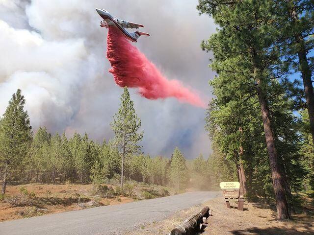 In this photo provided by the Bootleg Fire Incident Command, a plane drops retardant near Mitchell Monument in the Bootleg Fire, July 19, 2021.