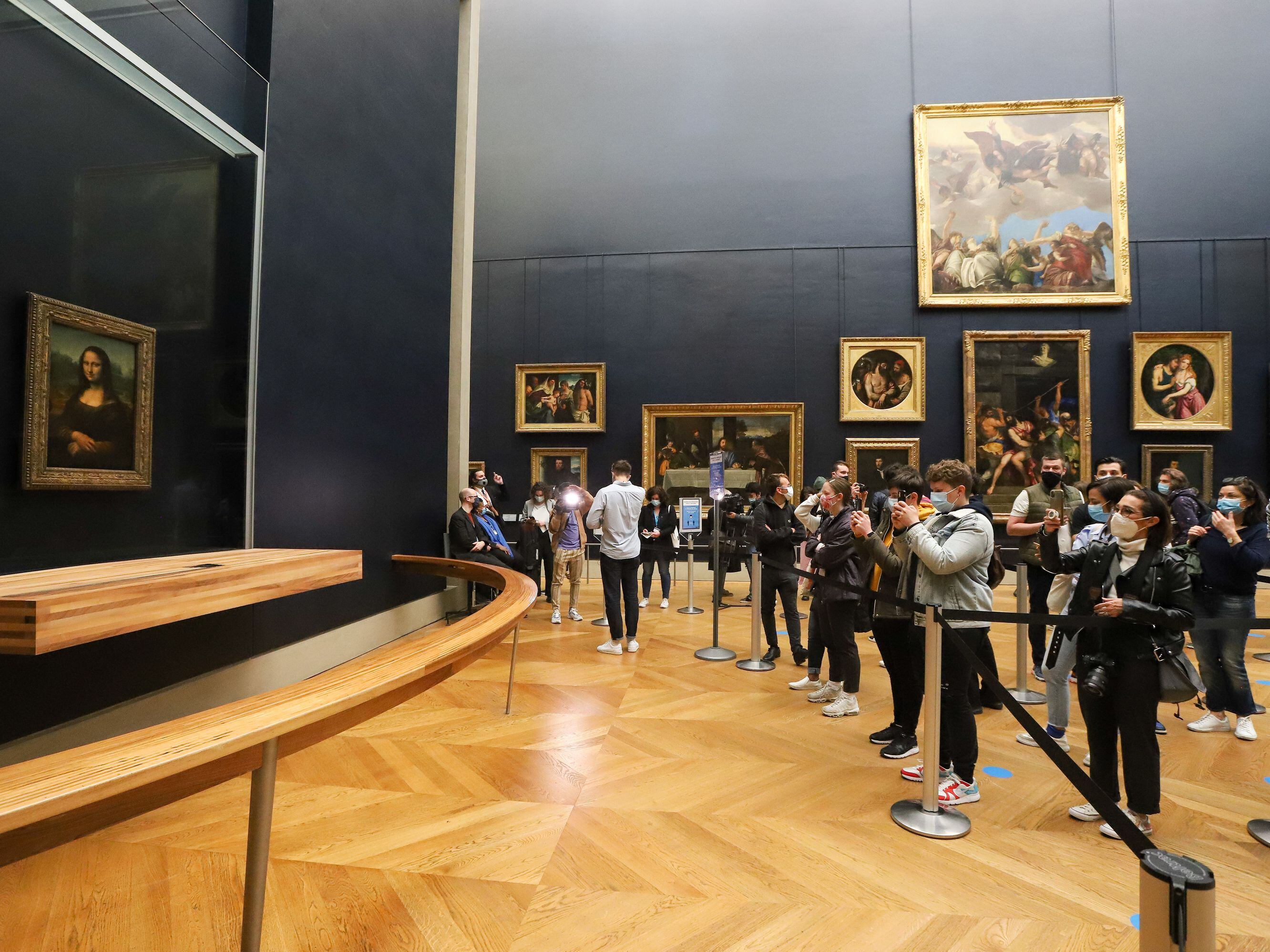 A visitor photographs the painting the Mona Lisa by Italian artist Leonardo Da Vinci on display in a gallery at the Louvre on May 19, 2021 in Paris.