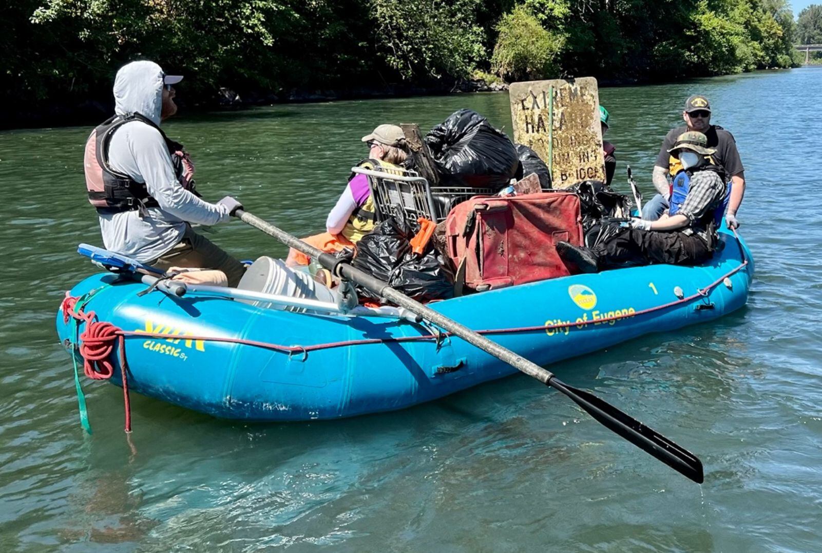 In this provided photo, volunteers with Willamette Riverkeeper use a raft to carry trash found along the Willamette River in Eugene in 2022.